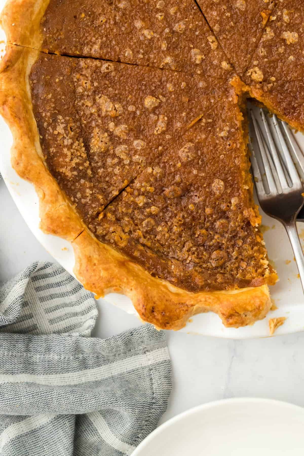 Overhead shot of a full pumpkin pie with a slice cut out and a couple of forks