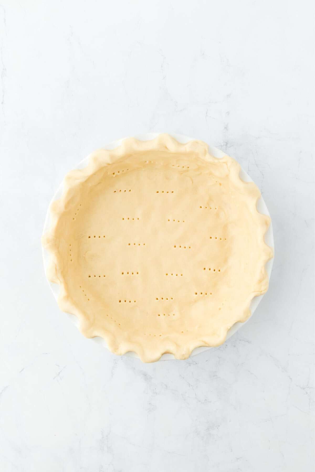 Overhead shot of a raw pie crust with tiny holes and crimped edges