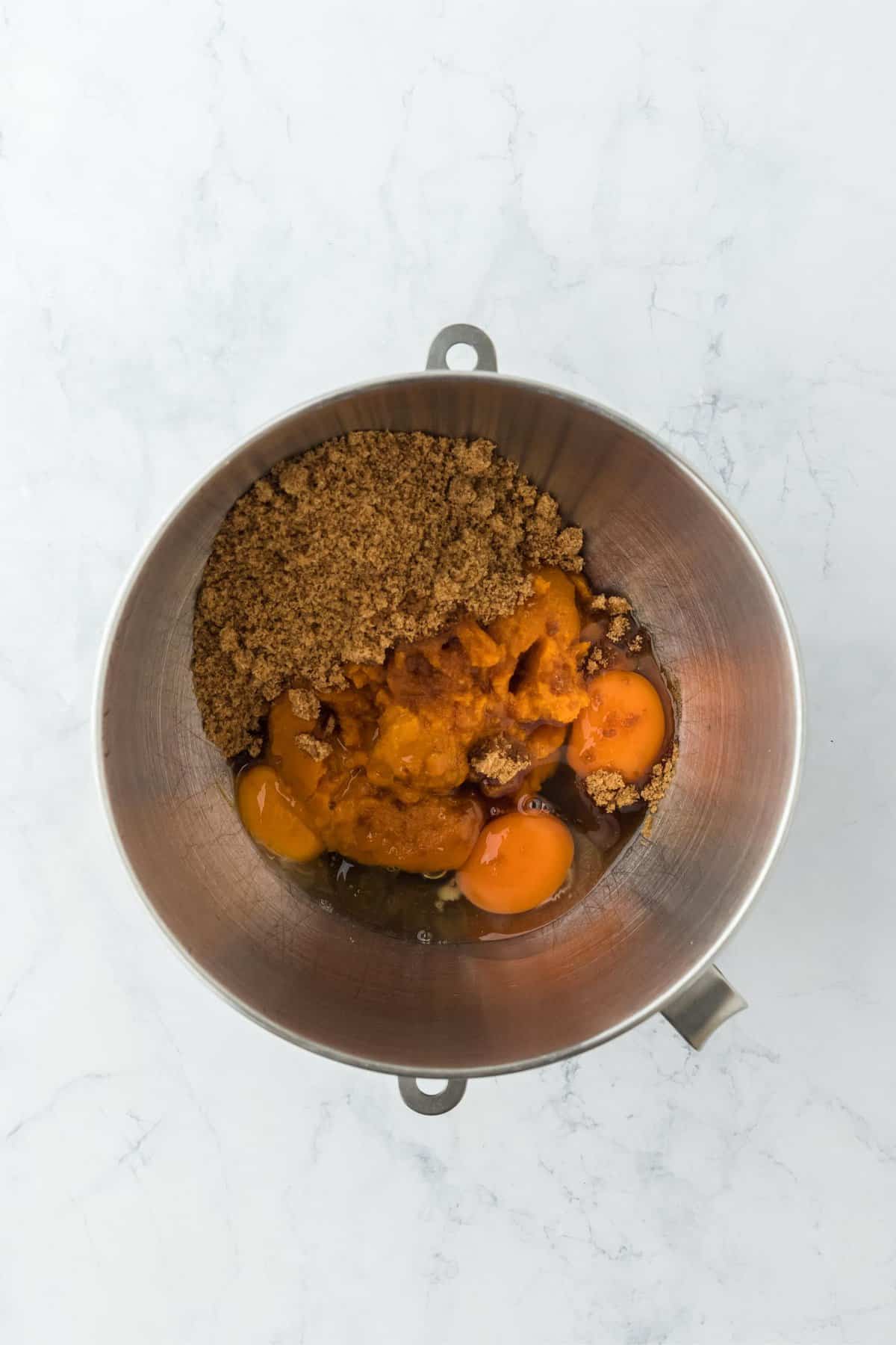 Overhead shot of a mixing bowl with pumpkin pie filling ingredients, including pumpkin puree, sugar and eggs