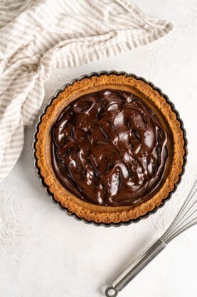 Chocolate ganache spread on a pumpkin pie against a white background