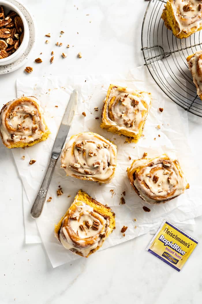 Cinnamon rolls scattered on the parchment paper on a white background