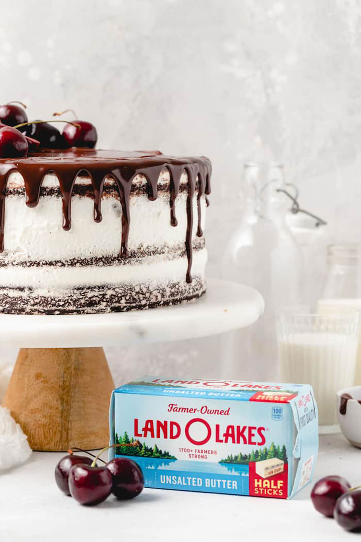 A side angle of black forest cake recipe on white and wood stand with a box of Land O Lakes butter