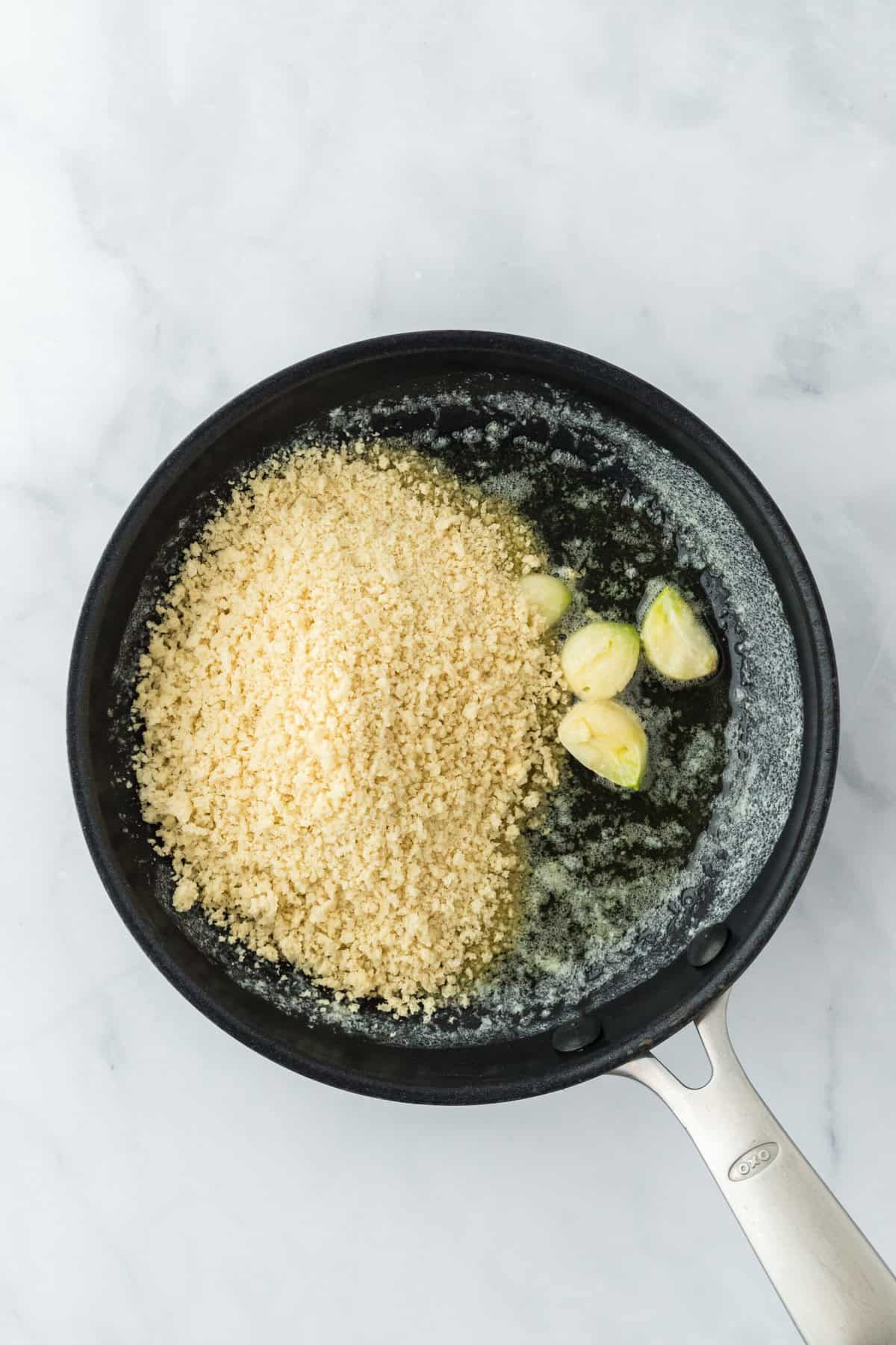 Panko in a skillet with butter and garlic cloves