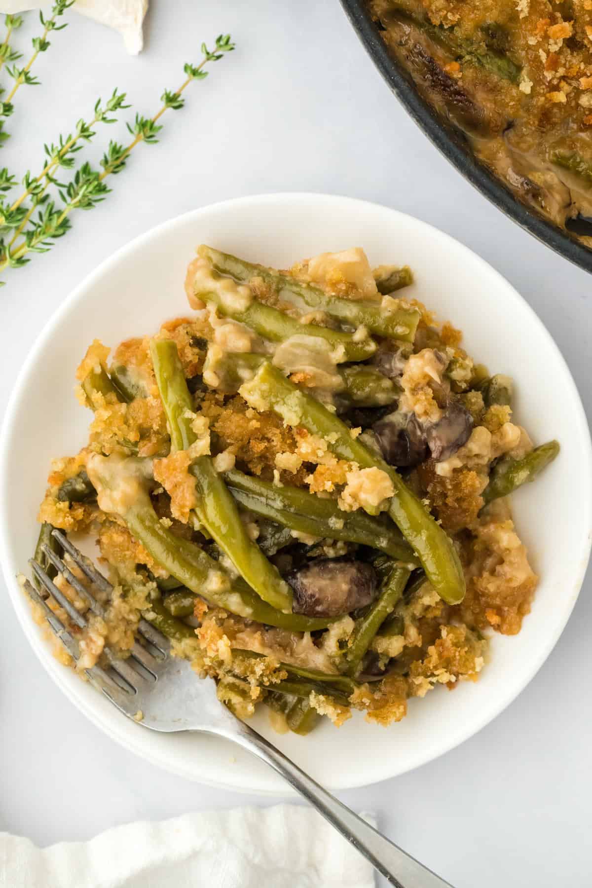 A serving of green beans casserole on a white plate on white background