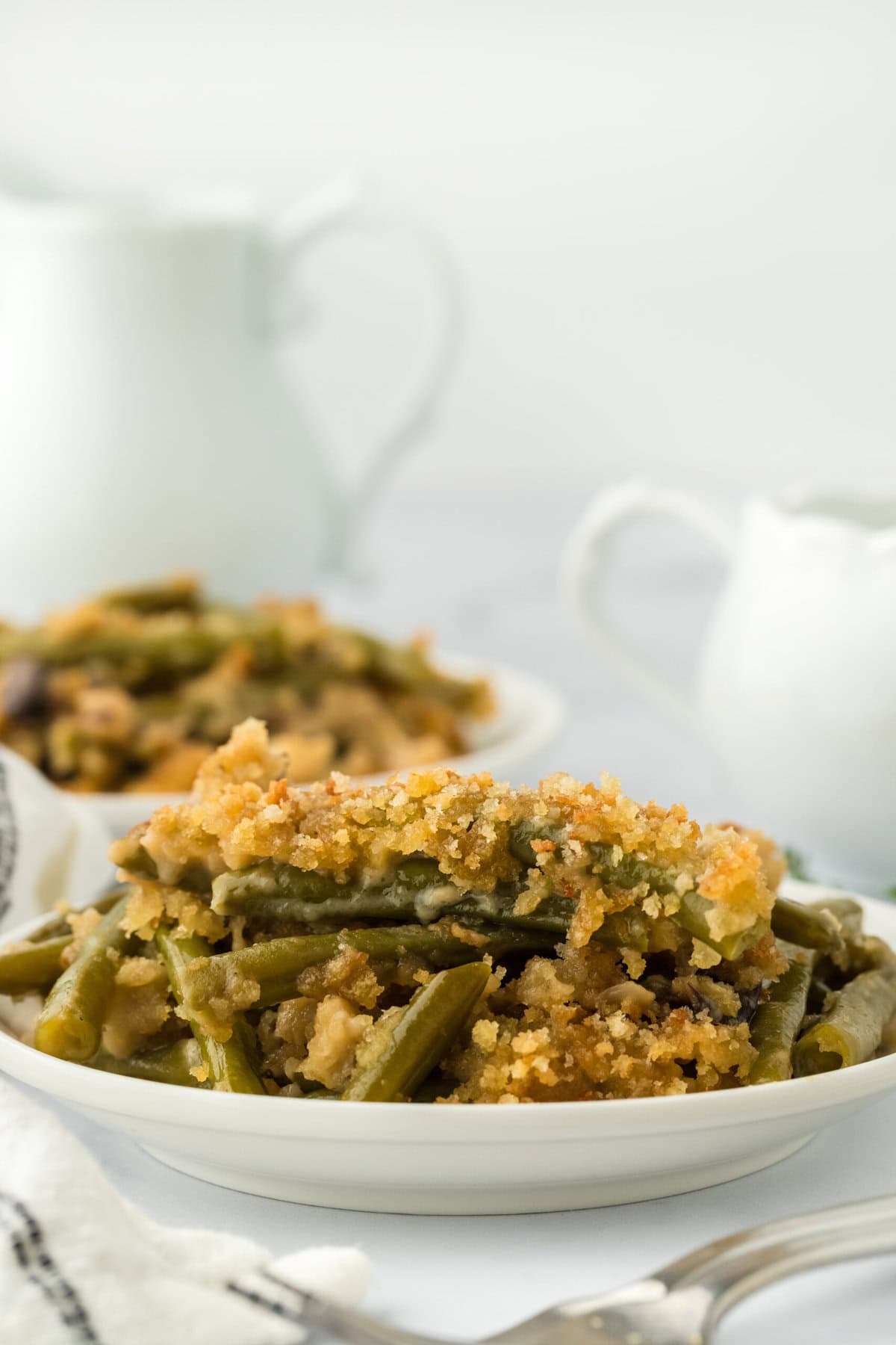 Green beans casserole on white dishes on a white background