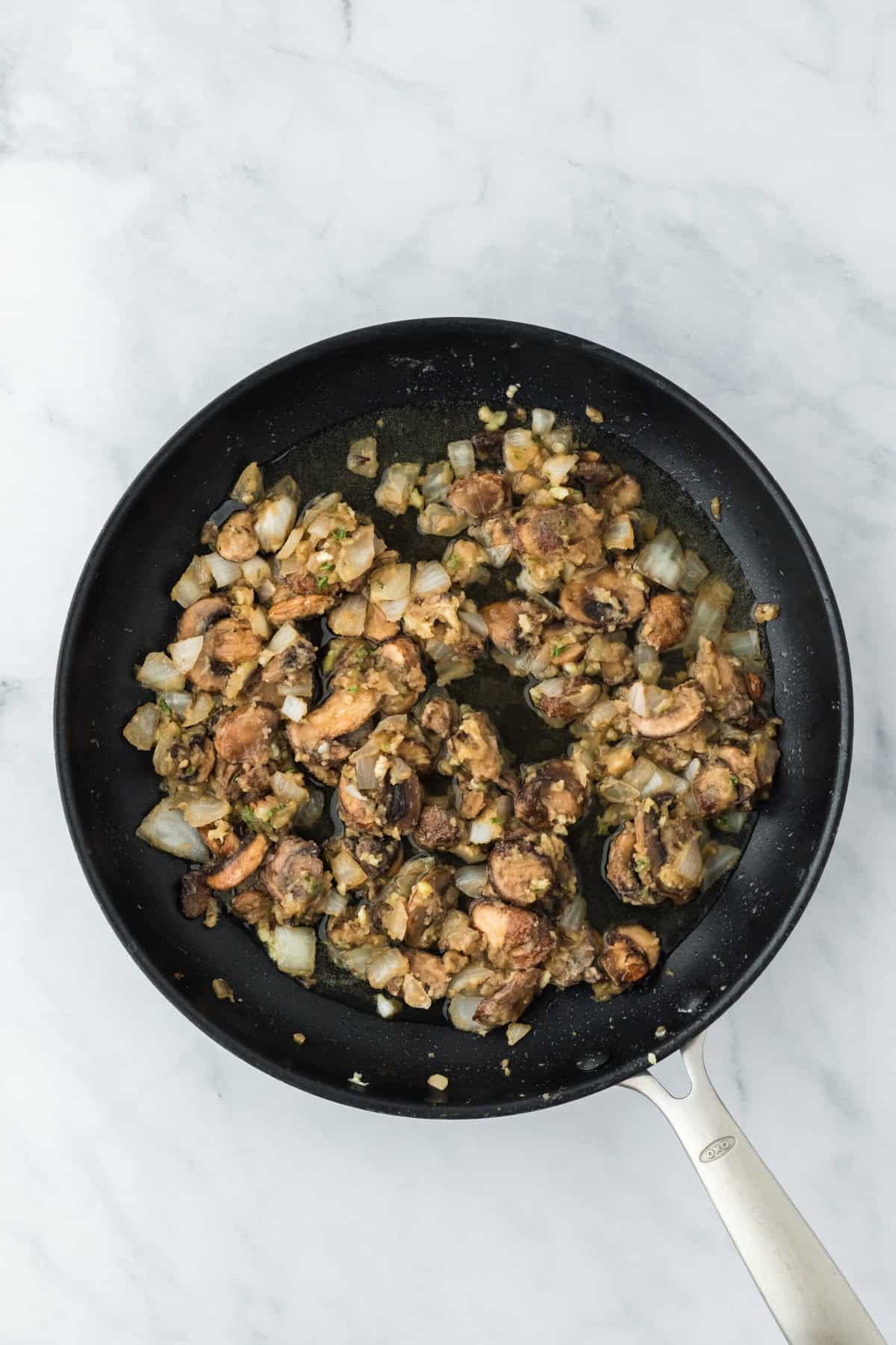 White wine stirred into mushroom and onions cooking in skillet