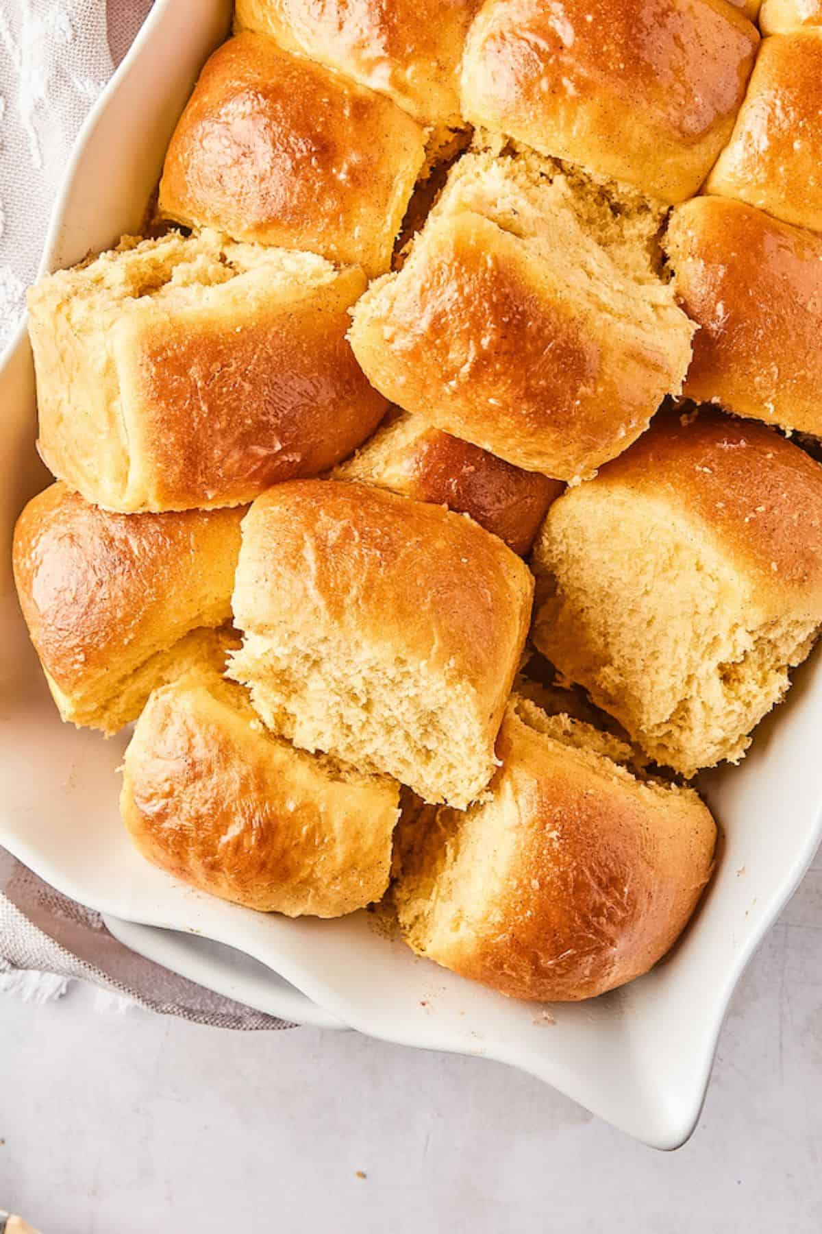 Close-up of golden, shiny honey butter dinner rolls in a baking dish, showcasing a soft and fluffy texture