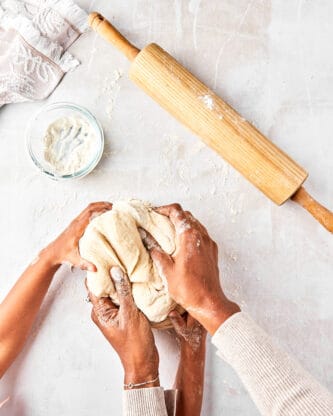 Black female hands and little black girl hands kneading dough