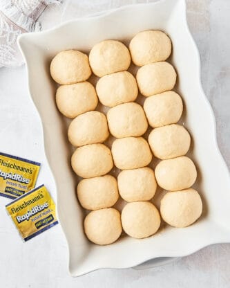 Dinner roll dough in a white casserole dish waiting to rise