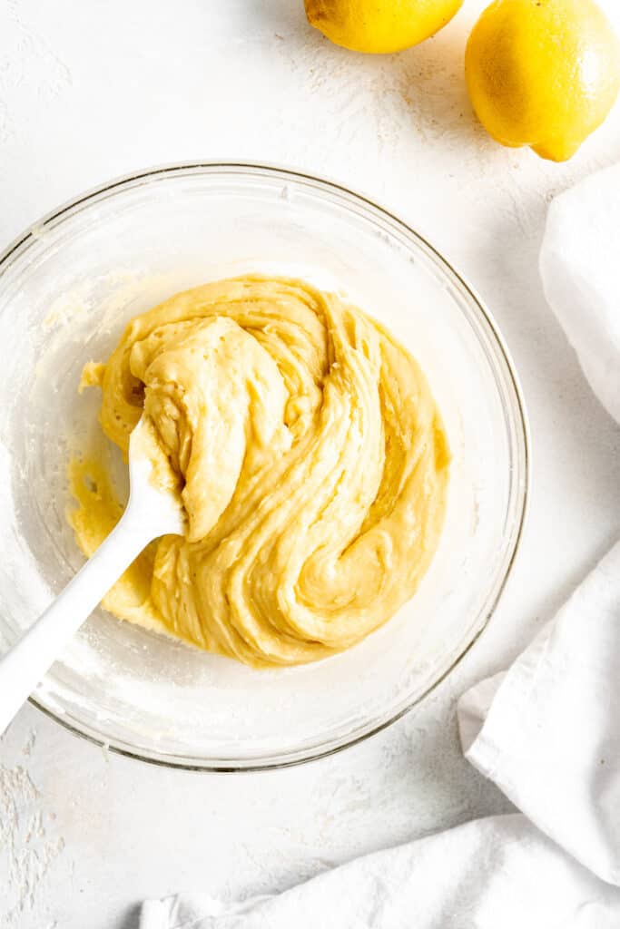 Dough in a glass bowl with a white spatula inside the dough after folding together