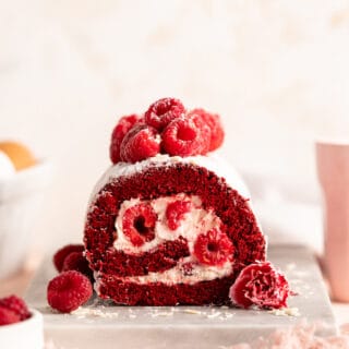 A straight on look at a red velvet cake roll piled high with raspberries ready to serve