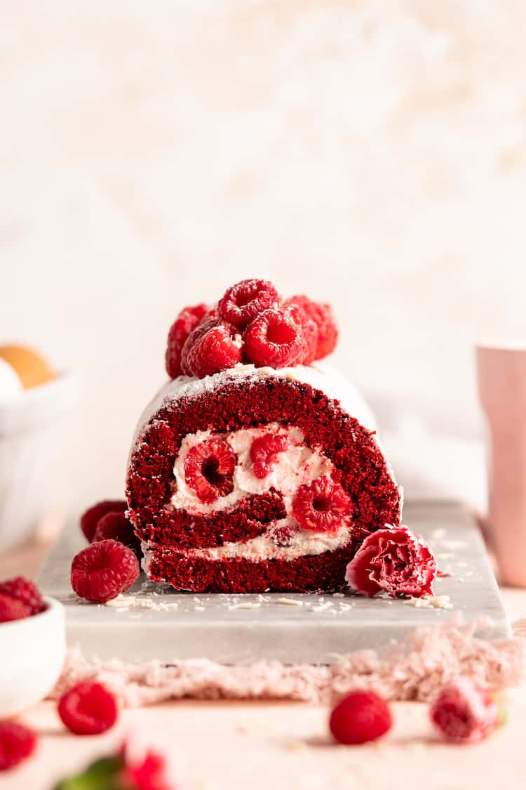 A straight on look at a red velvet cake roll piled high with raspberries ready to serve