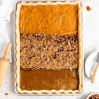 An overhead shot of a sheet pan pie baked with sweet potato pie, pecan pie and pumpkin pie fillings against a white background