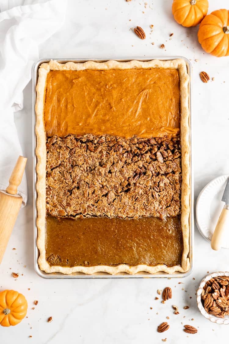 An overhead shot of a sheet pan pie baked with sweet potato pie, pecan pie and pumpkin pie fillings against a white background