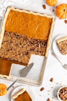 An overhead shot of a sheet pan pie baked with sweet potato pie, pecan pie and pumpkin pie fillings against a white background with a few slices cut to serve on an angle