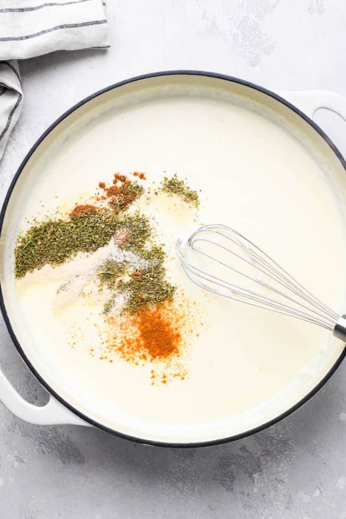 Spices being whisked into a cream sauce