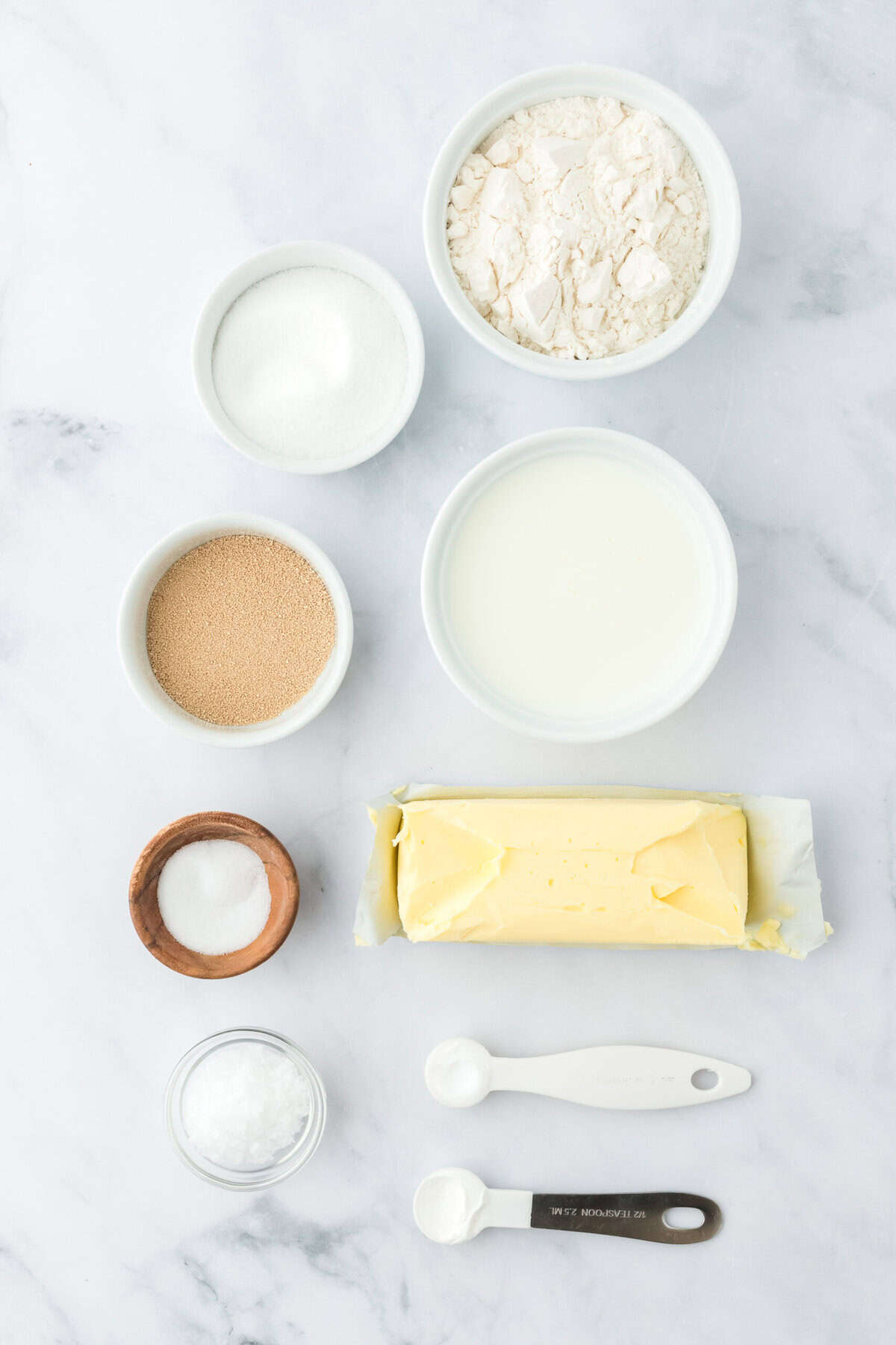 Butter, dry ingredients and yeast in small white bowls on white background