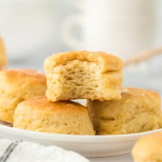 One eaten angel biscuit sitting on top of a pile of biscuits on white backgrorund