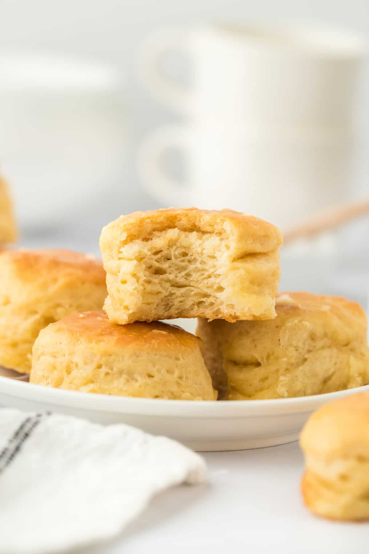 One eaten angel biscuit sitting on top of a pile of biscuits on white backgrorund