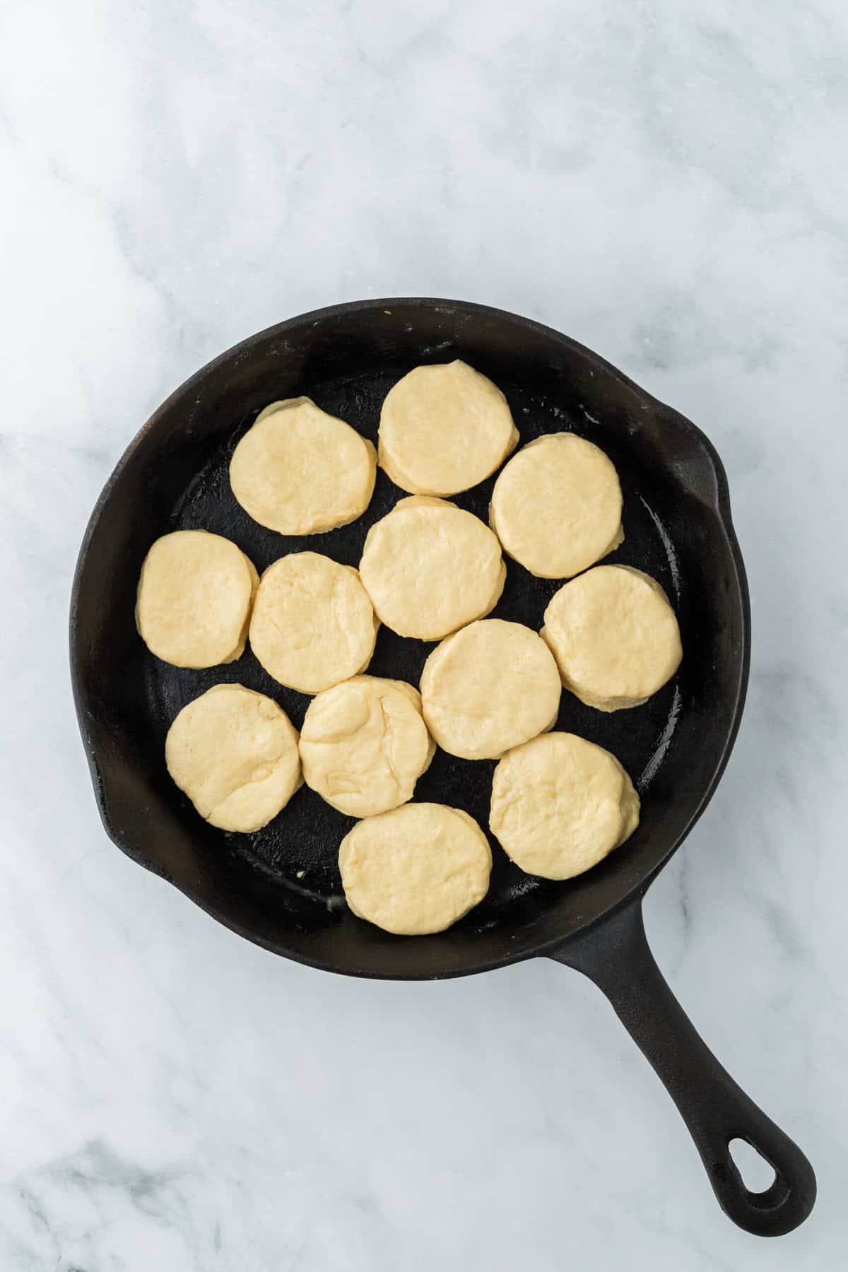 Cut biscuit dough in a cast iron skillet on white countertop