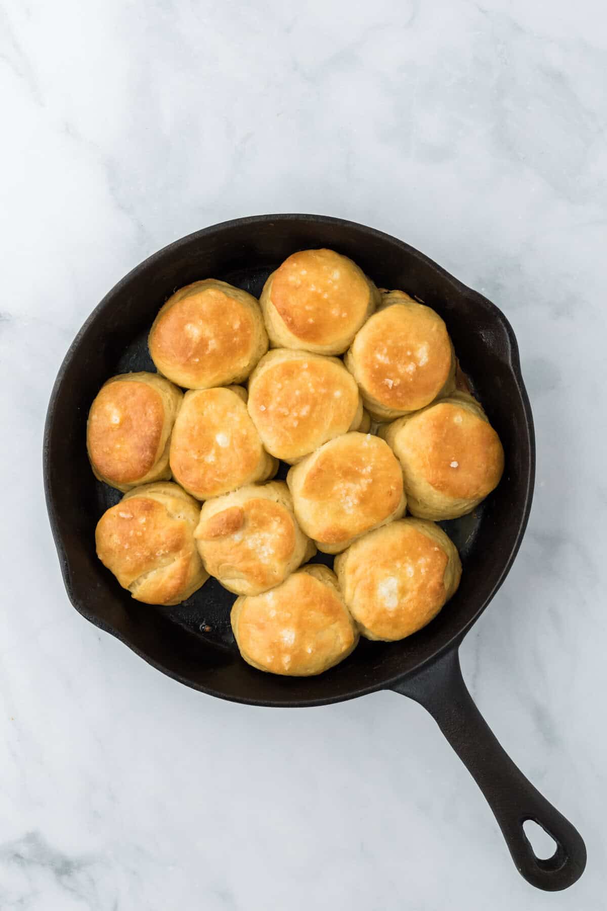 Baked angel biscuits in a cast iron skillet ready to enjoy on white countertop