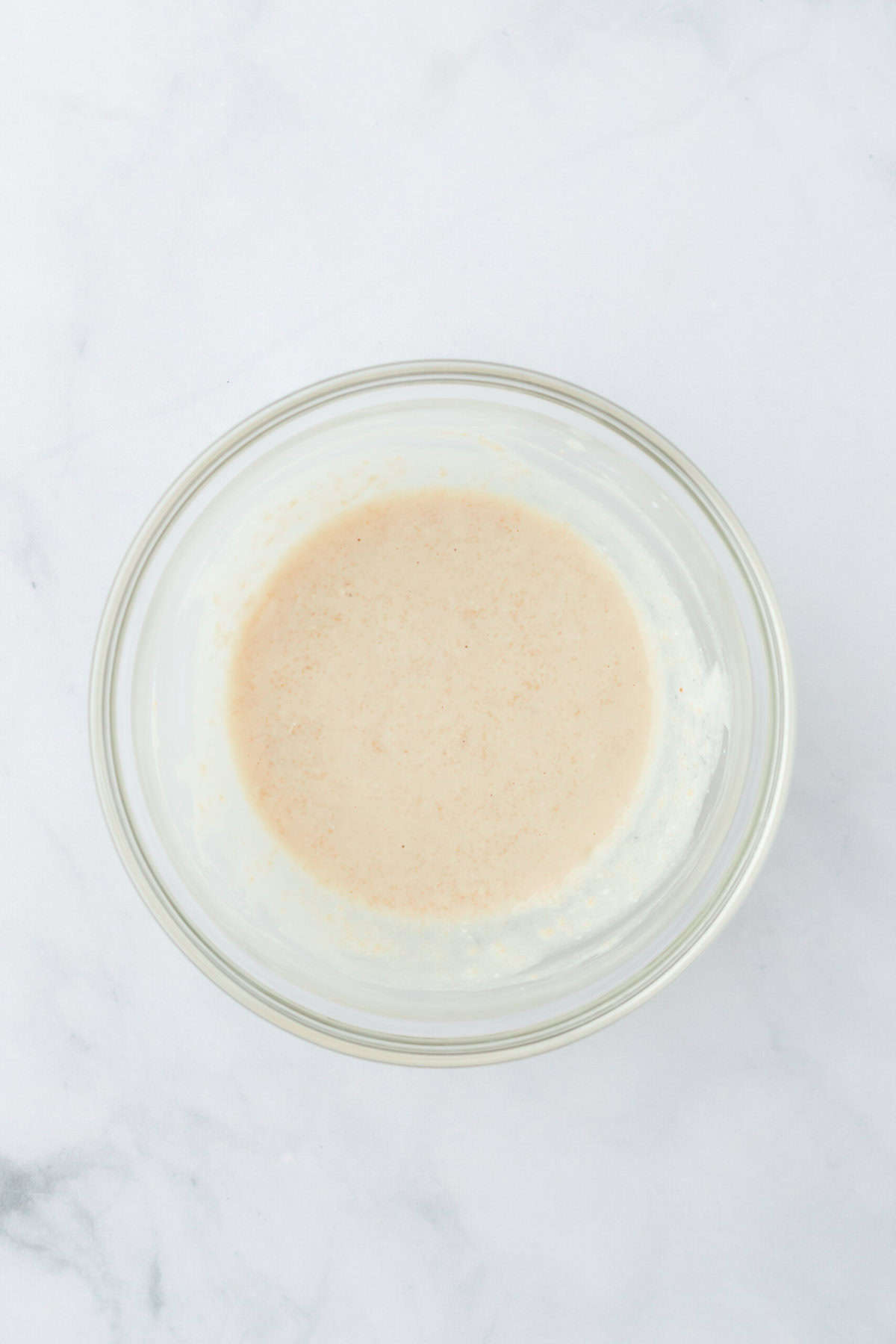 Buttermilk and yeast added to a small bowl with sugar on white countertop