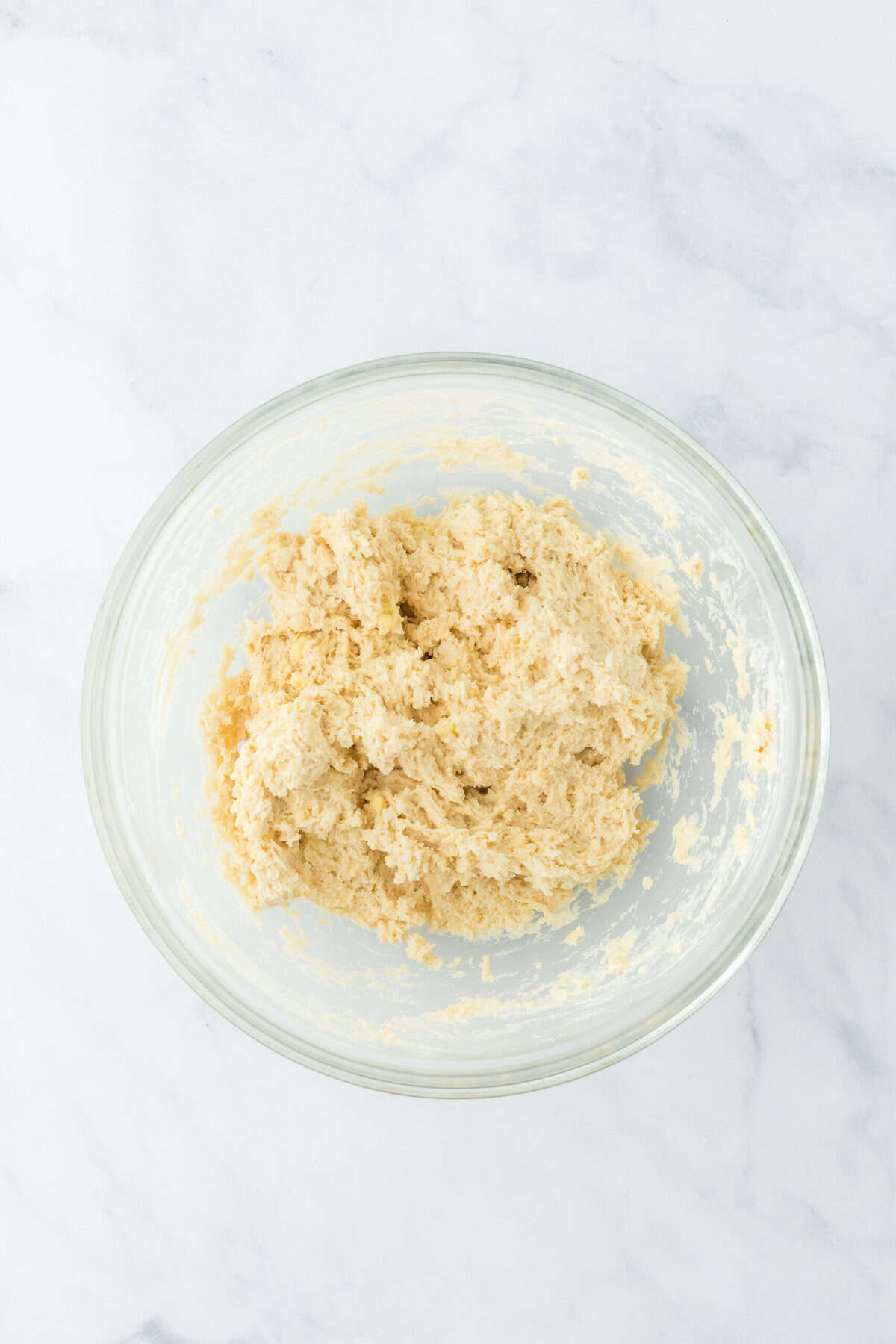 Shaggy biscuit dough formed in a glass bowl on white countertop