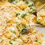 A spoonful of broccoli cheese casserole being lifted, showing a gooey texture with broccoli and cracker topping