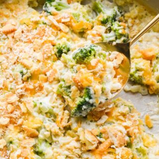 A spoonful of broccoli cheese casserole being lifted, showing a gooey texture with broccoli and cracker topping