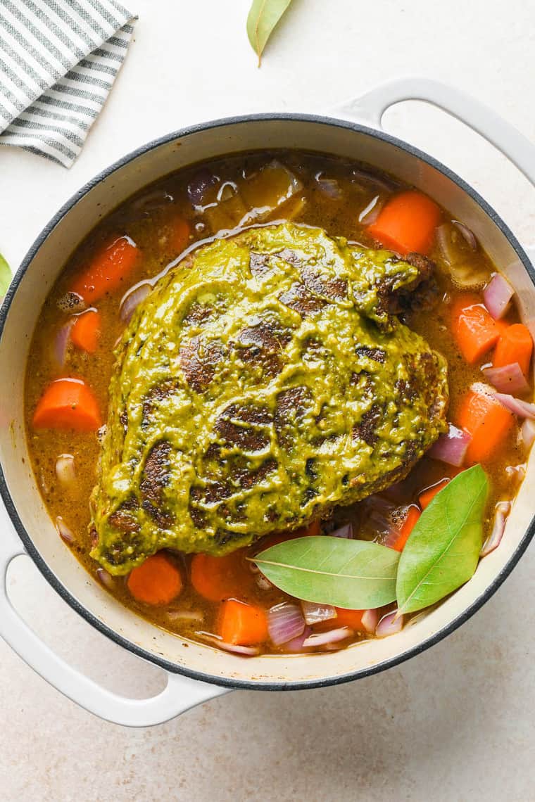 A beef roast in liquid and rubbed with pesto before baking