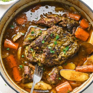 A delicious chuck roast in a nest of delicious juices in a dutch oven ready to roast