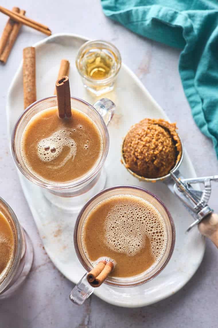 A top down shot of hot buttered rum in two glasses with cinnamon sticks as garnish