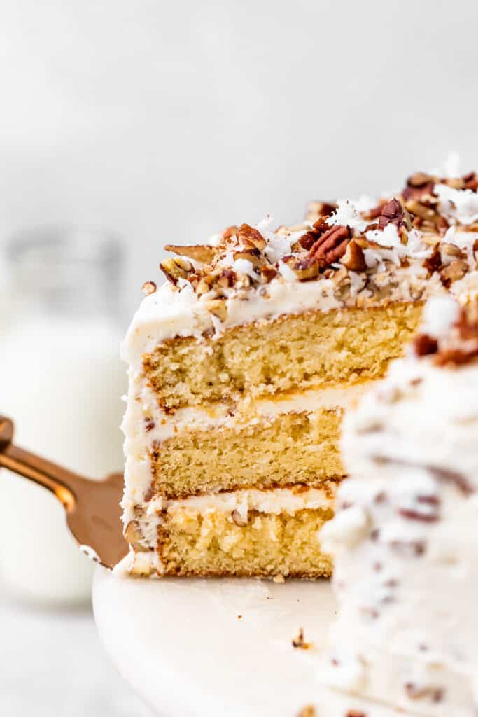 A close up of sliced Italian Cream Cake with a slice on a gold server