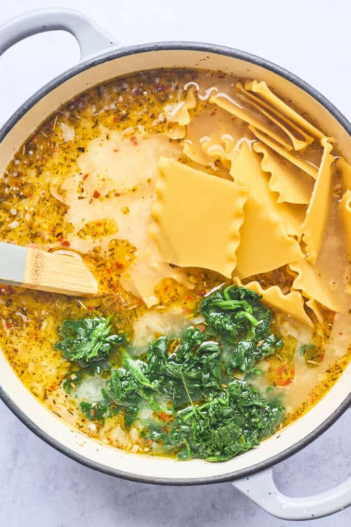 Lasagna noodles being mixed into a brothy soup