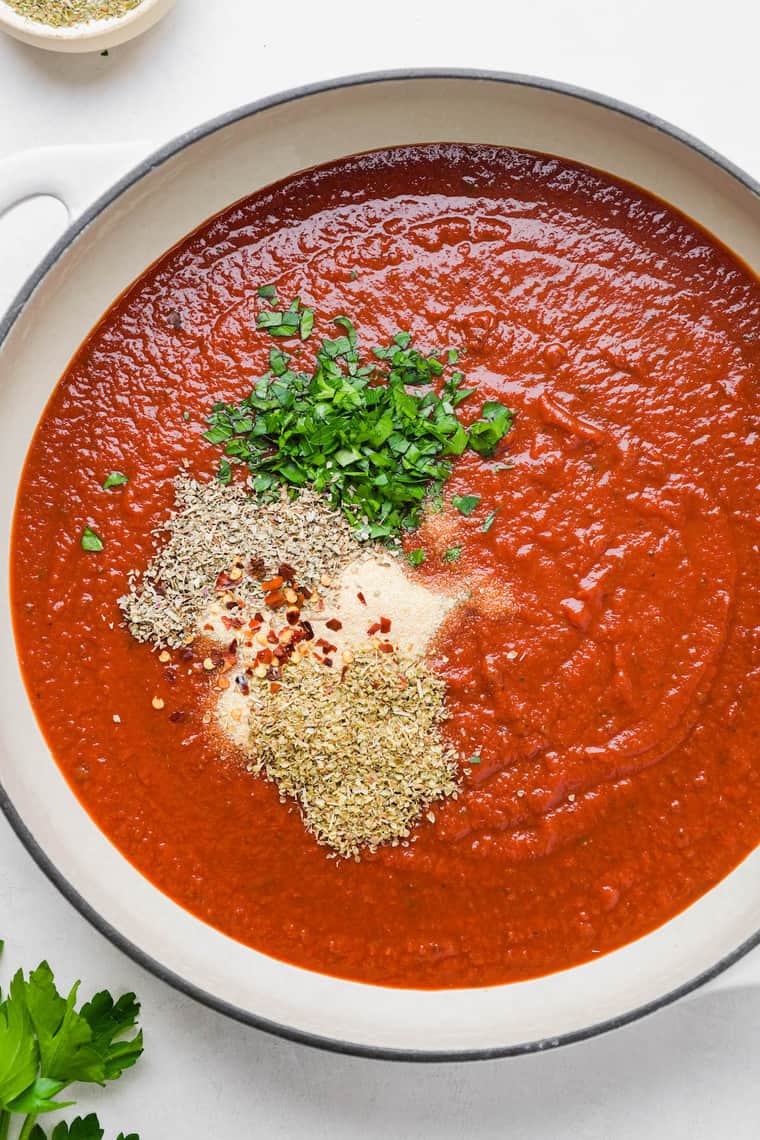 A pizza sauce being simmered with herbs and spices