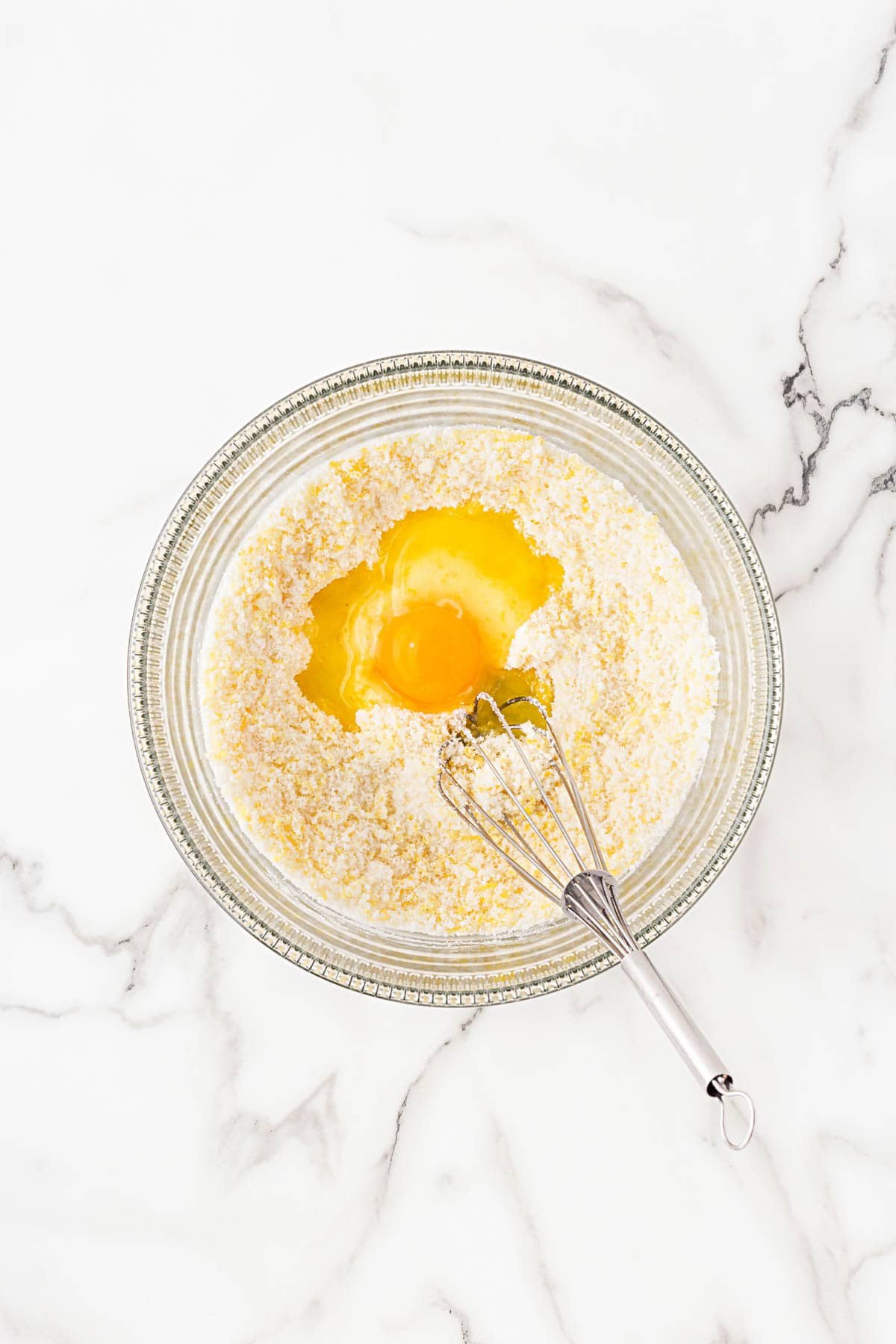 Eggs added to the dry ingredients in a mixing bowl, ready to be whisked