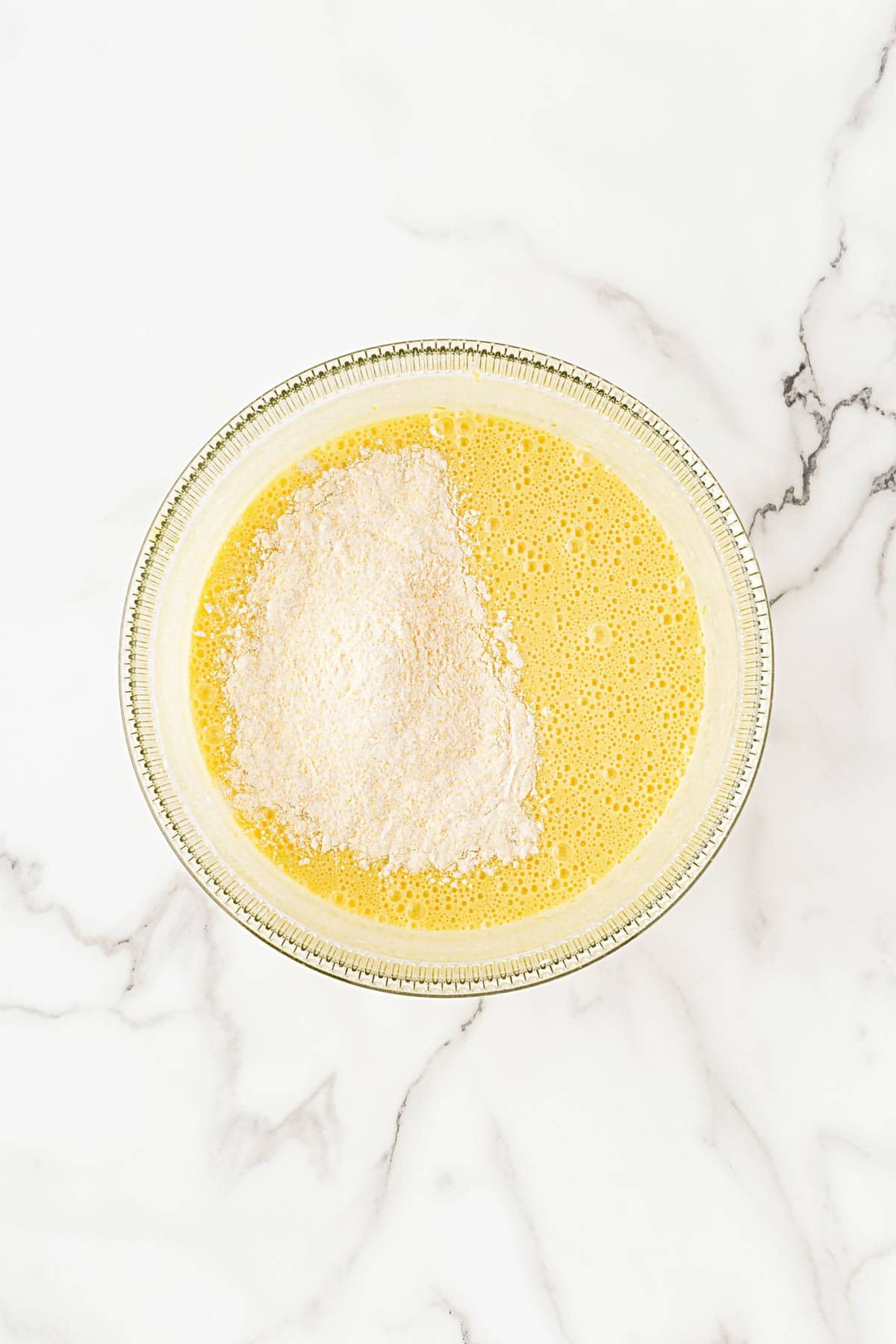 Flour mixture added to the wet batter in a glass mixing bowl