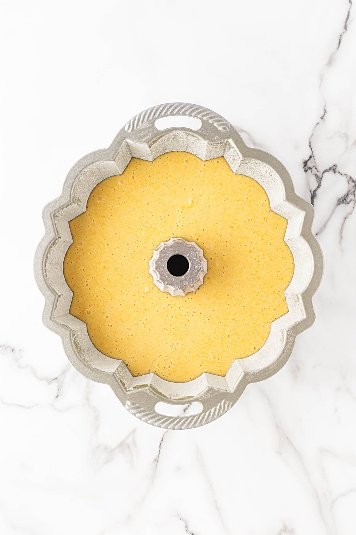 Lemon olive oil cake batter poured into a greased bundt pan