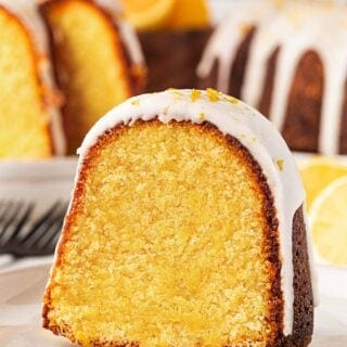 Closeup of a sliced lemon olive oil cake showing the moist, golden crumb with glaze on top and more cake in the background