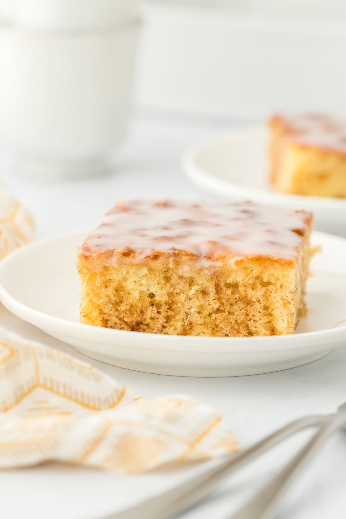Two slices of honey bun cake recipe on white plates against a white background