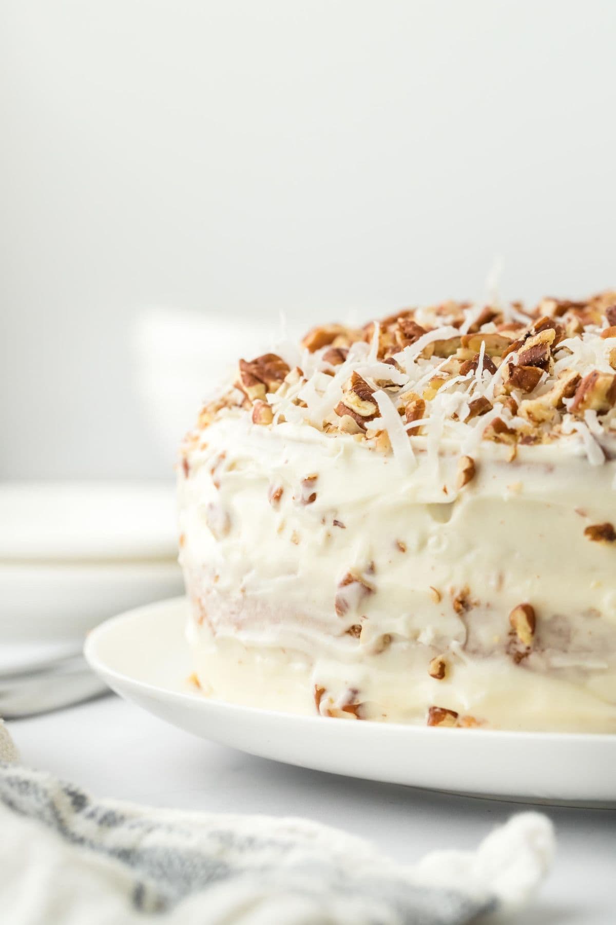 A side view of the Italian cream cake, highlighting the layers of frosting and the pecan-coconut topping.