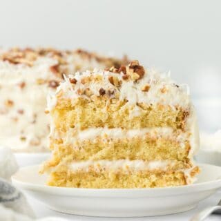 A slice of italian cream cake on a white plate ready to enjoy.