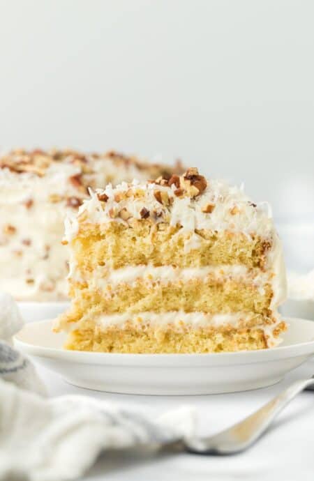 A slice of italian cream cake on a white plate ready to enjoy.