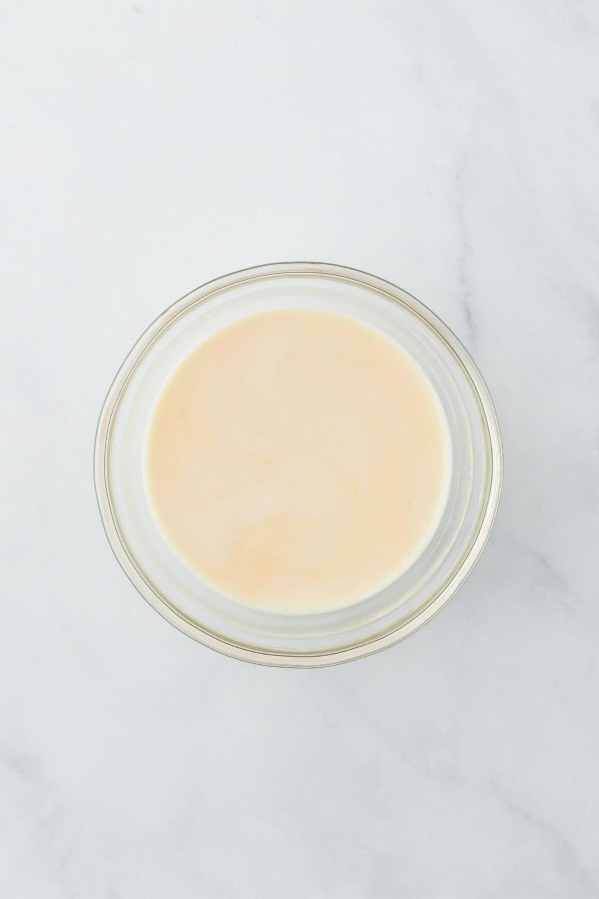 A bowl with the coconut milk soak, on a white marble surface