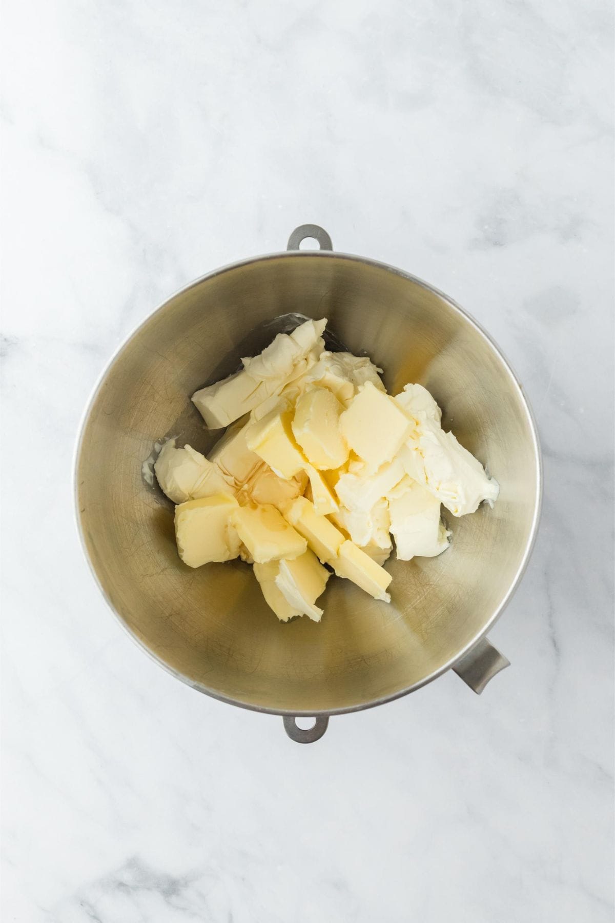 Cream cheese and butter cubes in a mixing bowl, prepared for frosting