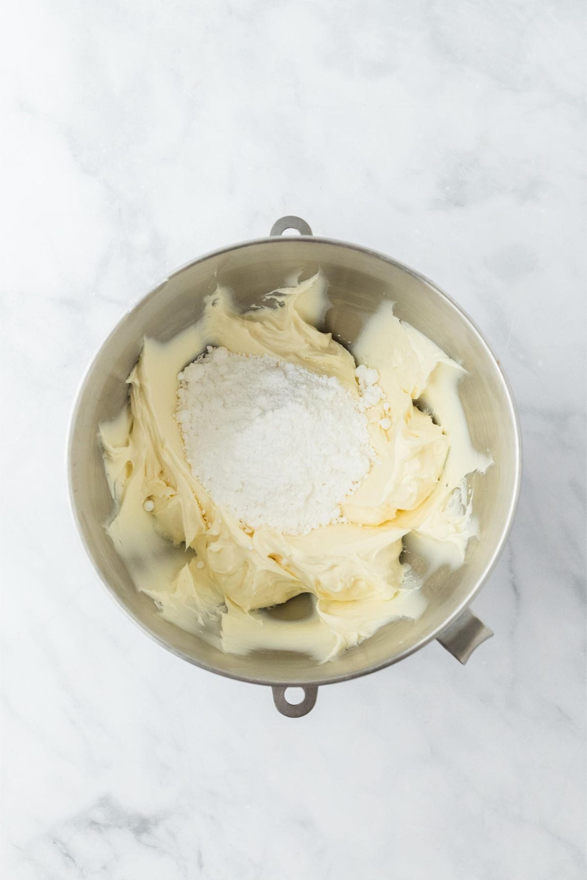 Cream cheese and butter mixture with powdered sugar being added