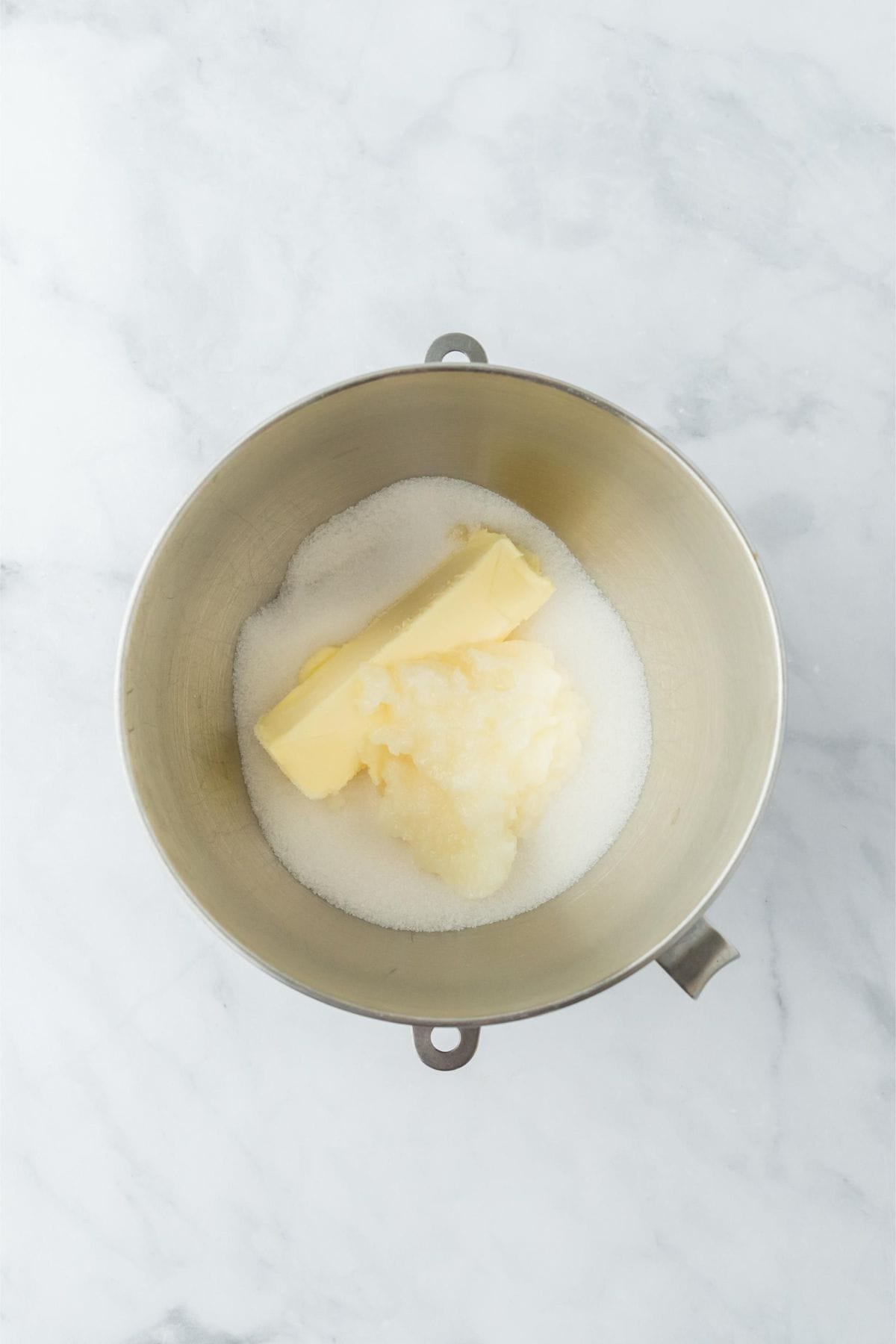 A mixing bowl with butter, sugar, and coconut oil ready to be mixed