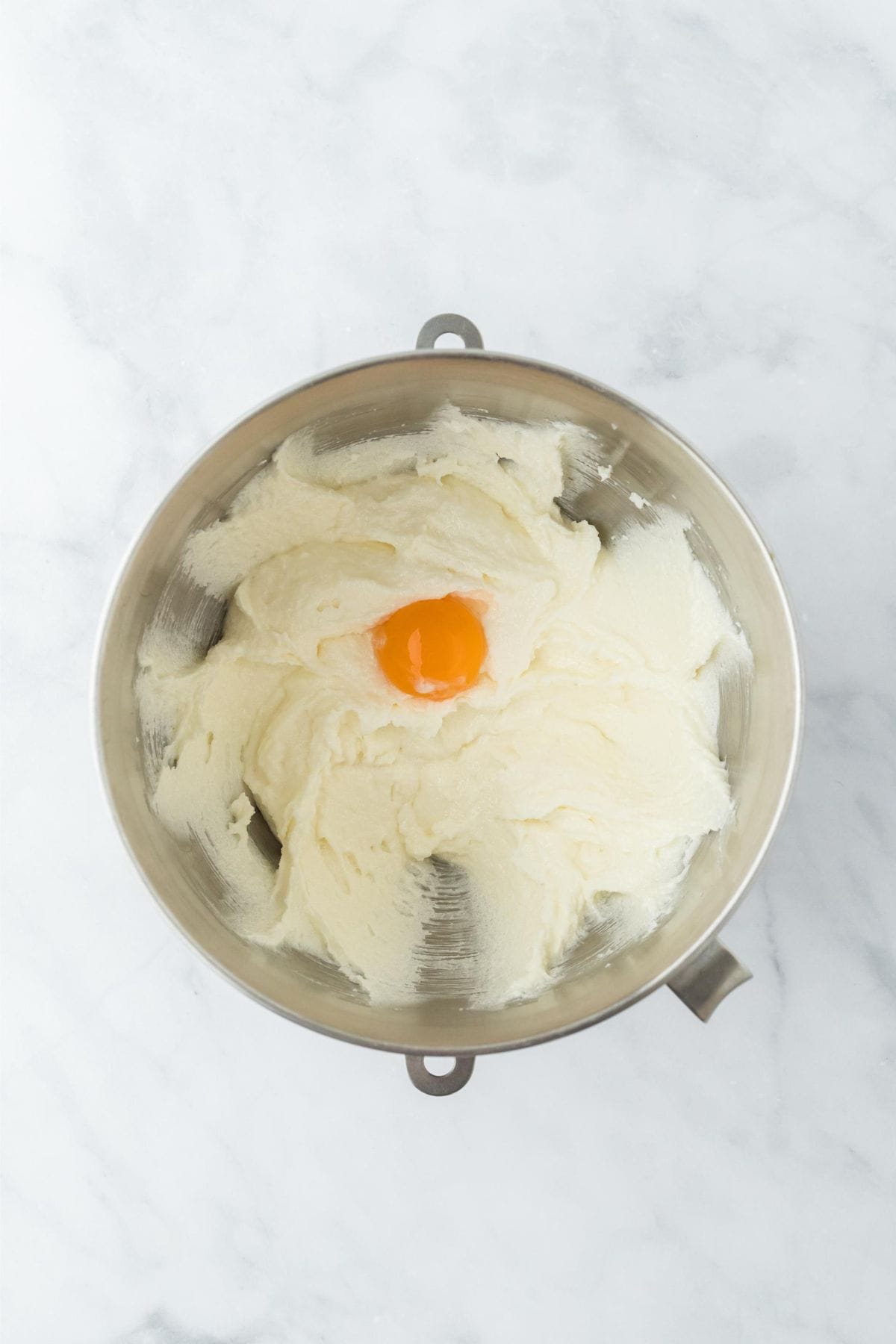 A mixing bowl with the creamed butter and sugar, with a single egg yolk added in the center