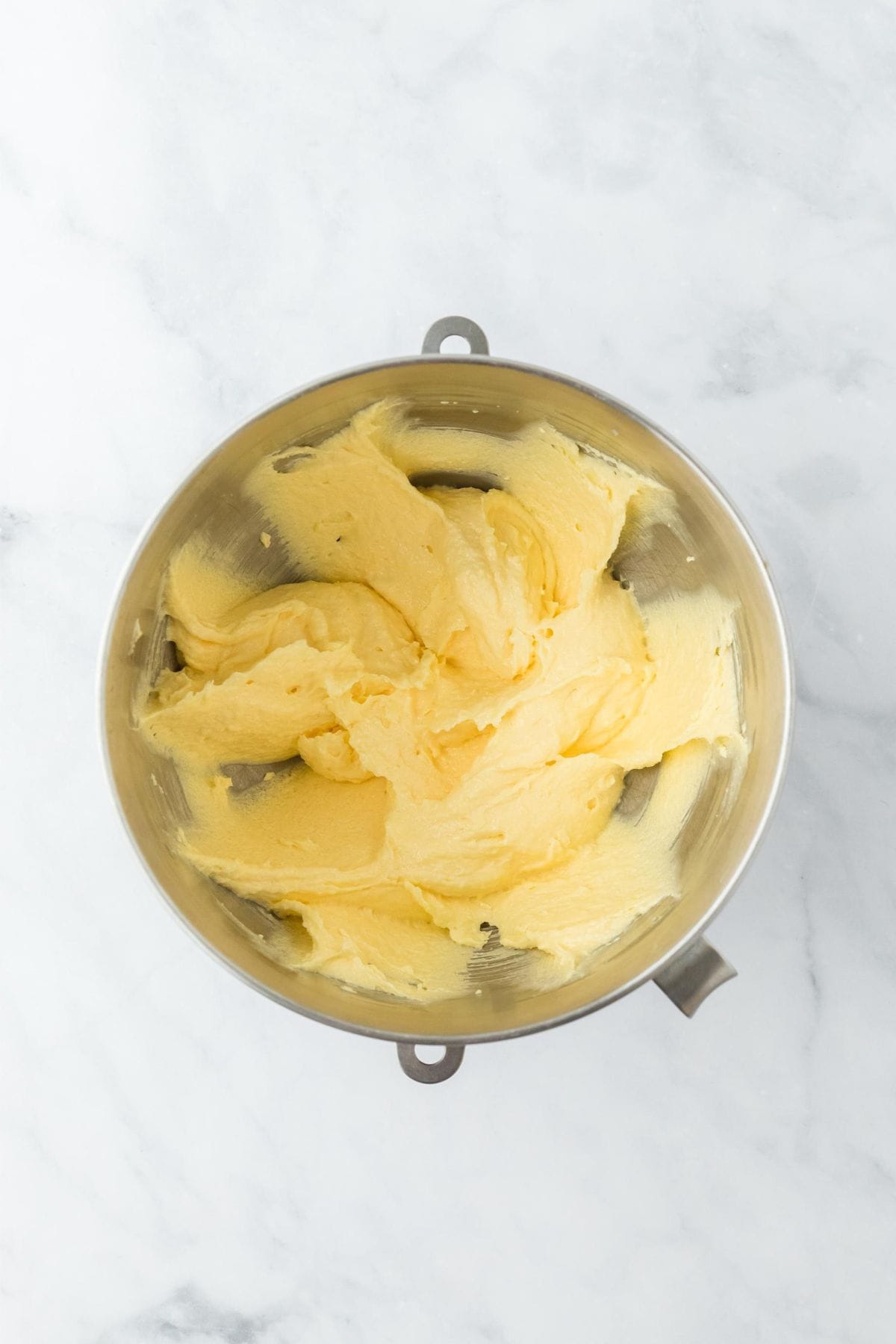 Creamed butter and sugar, now with the egg incorporated, in a light yellow color in a metal bowl