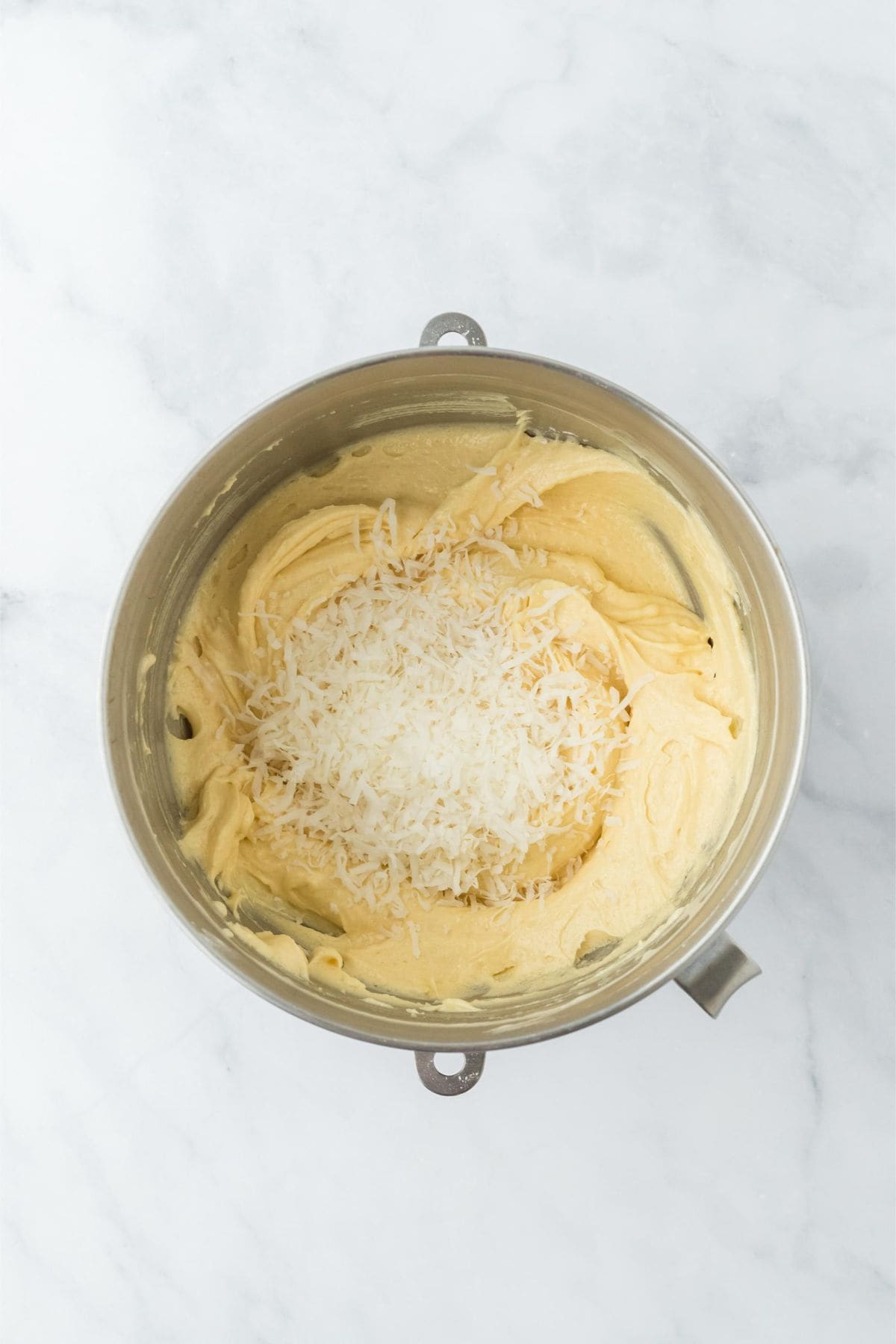 Mixing bowl with the cake batter, with shredded coconut added to the mixture